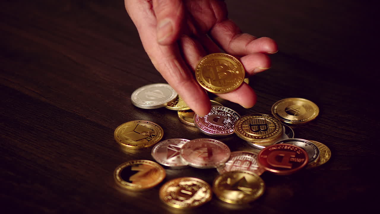 Man hand holding crypto coins and golden bitcoin on a table