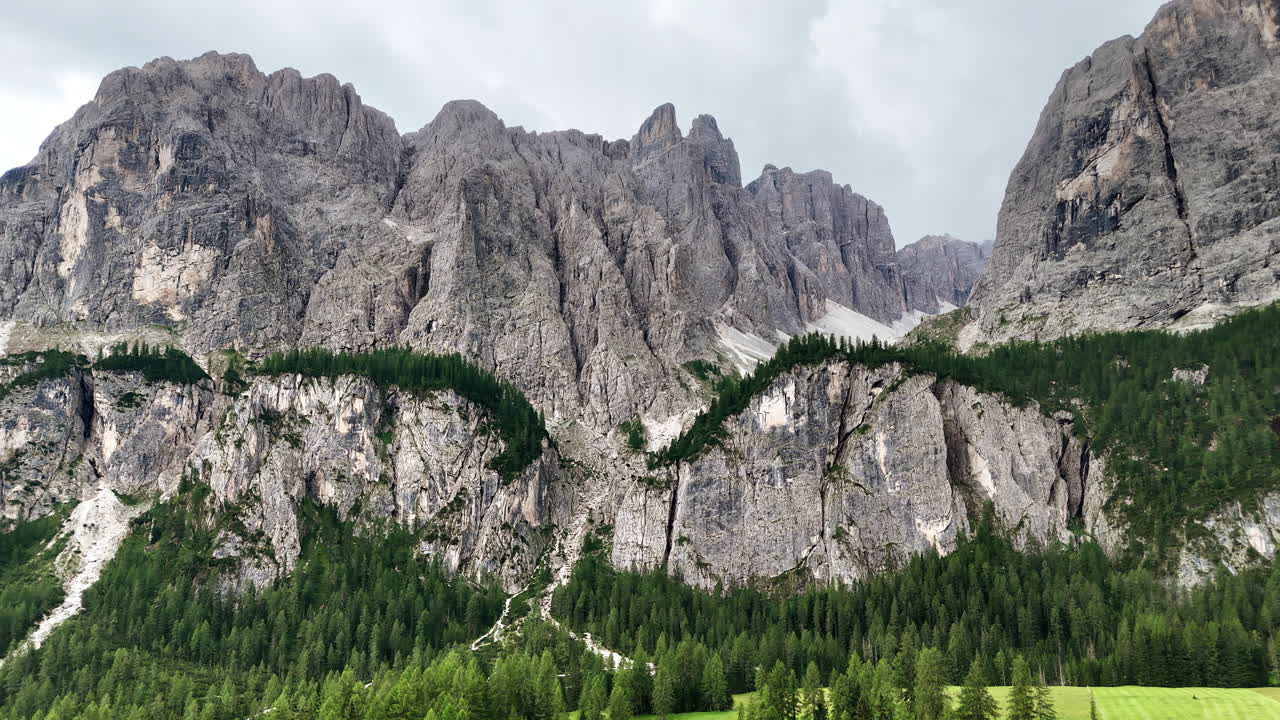 Luftfoto med drone af stejle kalkstensklipper og alpineskov i Dolomitterne. Den barske bjergkæde skaber et dramatisk naturlandskab i det nordlige Italien.