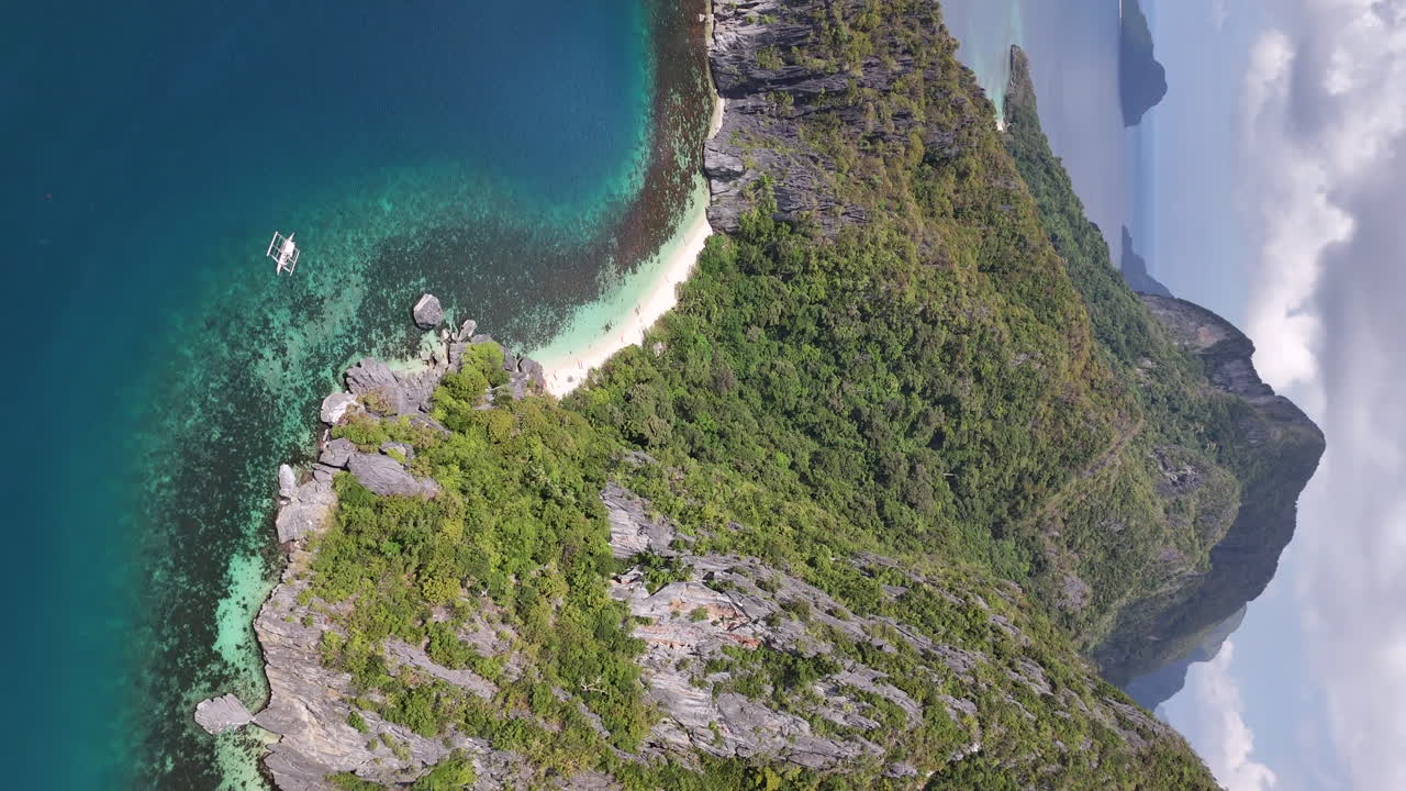 Drone footage of Coron Island, Philippines, where vibrant beaches meet dense greenery and rugged cliffs in an untouched paradise. Vertical video.