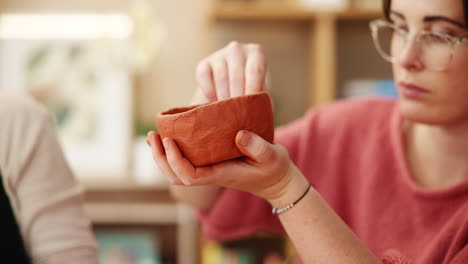 woman carefully working on a clay bowl