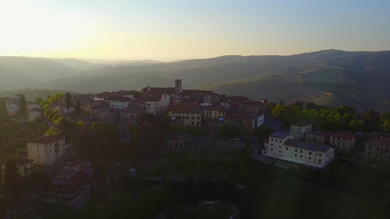 Una persona saluta il drone che poi esegue una ripresa in salita e a ritroso per rivelare una bellissima città nella campagna toscana