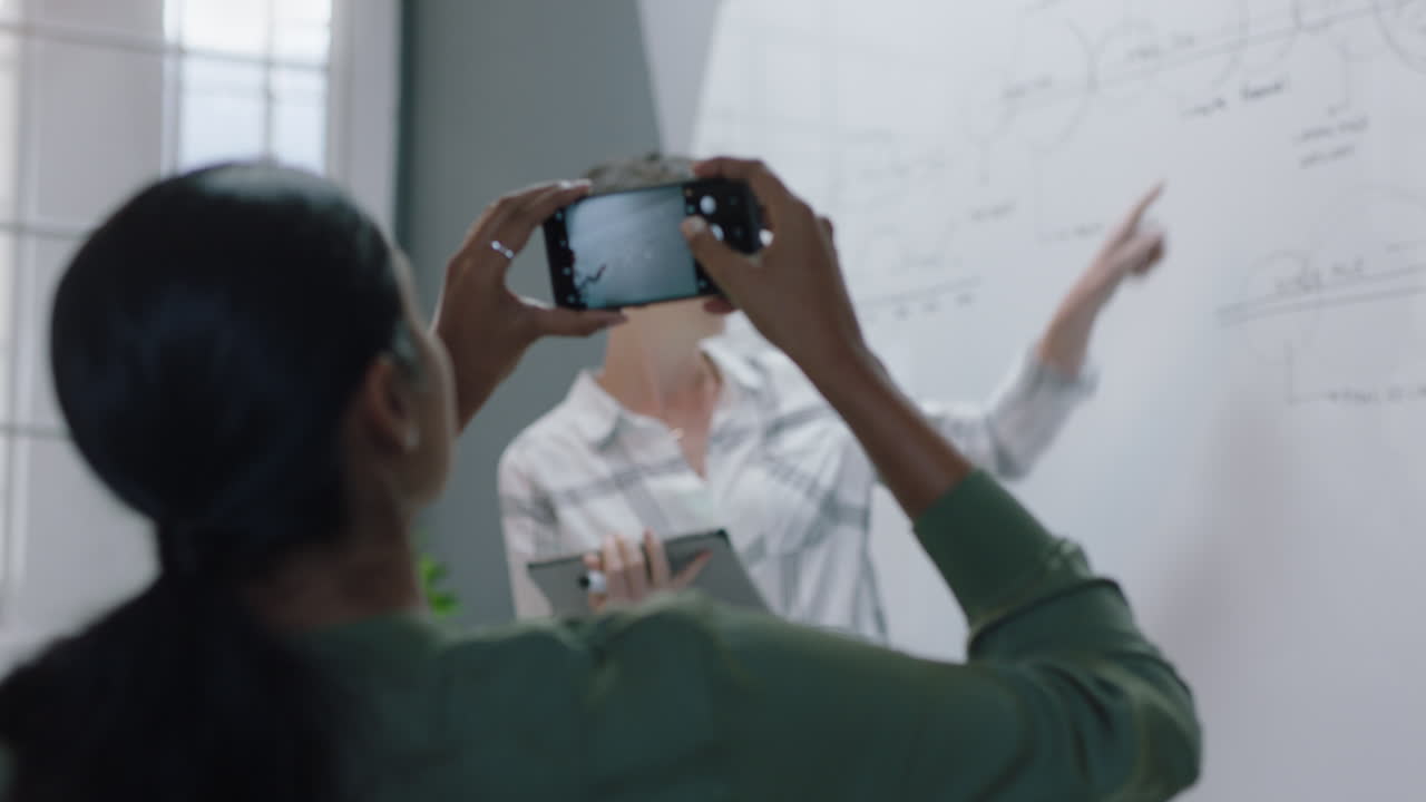 mujeres de negocios creativas diseñadores de lluvia de ideas trabajando juntos en un proyecto de diseño web mujer caucásica planificación estrategia de desarrollo utilizando investigación en línea escribir ideas en pizarra en la oficina moderna