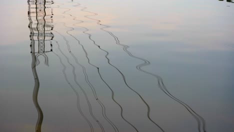 transmission-tower-power-grid-power-line-by-the-lake-over-the-mountain-reflection-in-rippling-lake-water