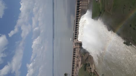 vertical format aerial orbit of hydro dam releasing spring flood water