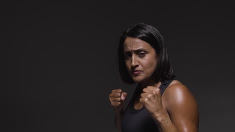 studio portrait of mature woman wearing gym fitness clothing exercising sparring at camera 3