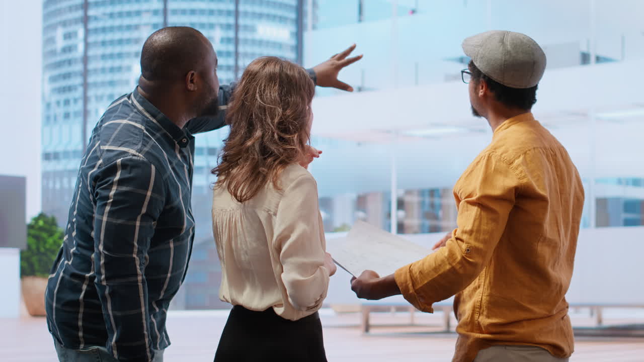 agente inmobiliario y clientes compartiendo la visión del diseño del espacio de trabajo en un recorrido por la oficina