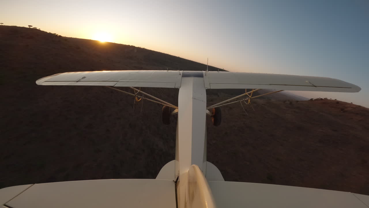 Piccolo aereo che plana sopra il crinale di un fiume in Kenya al tramonto