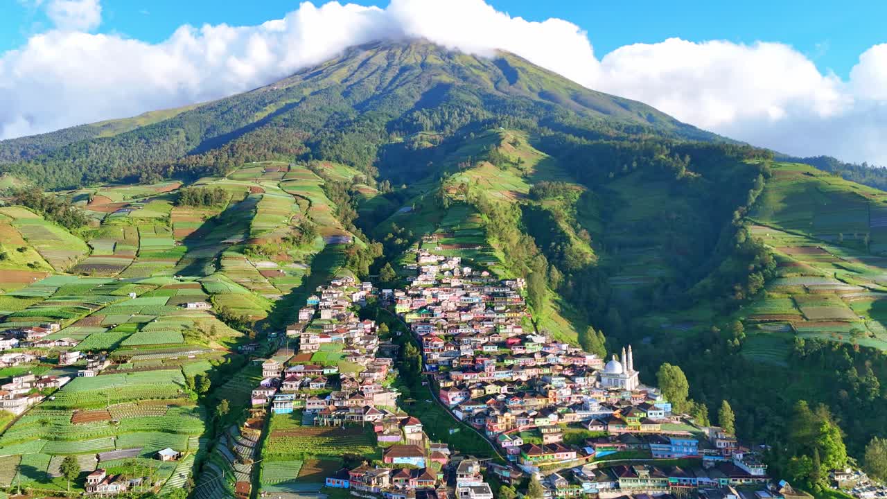 Drone view of a beautiful rural settlement nestled between green mountains with agricultural terraces and scenic landscape. Nepal Van Java Village, Mount Sumbing, Indonesia