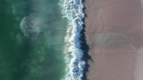 toma vertical del mar de blouberg con olas espumosas salpicando la costa en ciudad del cabo en sudáfrica