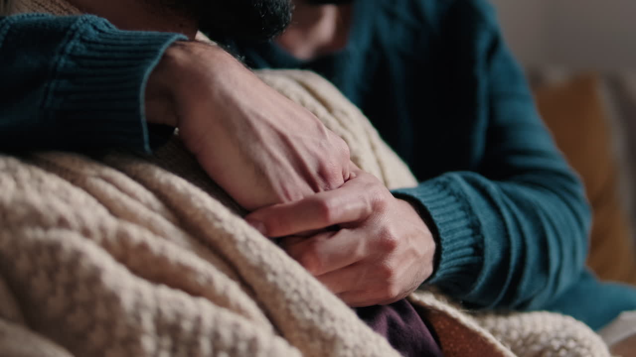 Gay Couple Embracing on Sofa at Home
