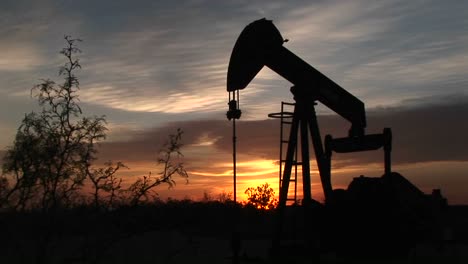 medium shot of a silhouetted oil pump turning in the new mexico desert 4