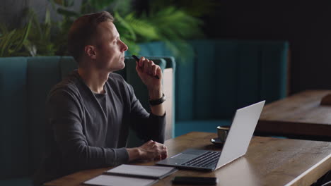 thoughtful serious young man student writer sit at home office desk with laptop thinking of inspiration search problem solution ideas lost in thoughts concept dreaming looking away