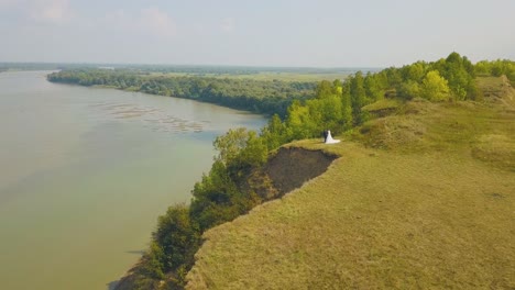 Das-Frisch-Verheiratete-Paar-Genießt-Den-Blick-Auf-Den-Fluss-Von-Der-Steilen-Uferantenne-Aus