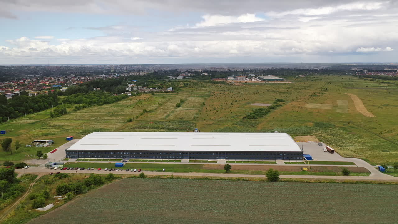 Contemporary business building. View from above on a modern industrial building surrounded by natural fields. Aerial view. Motion camera forward.