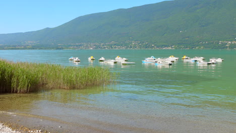 boats glide across the serene waters of lac du bourget, surrounded by picturesque mountains, enjoying a perfect day for paddling and relaxing in nature.