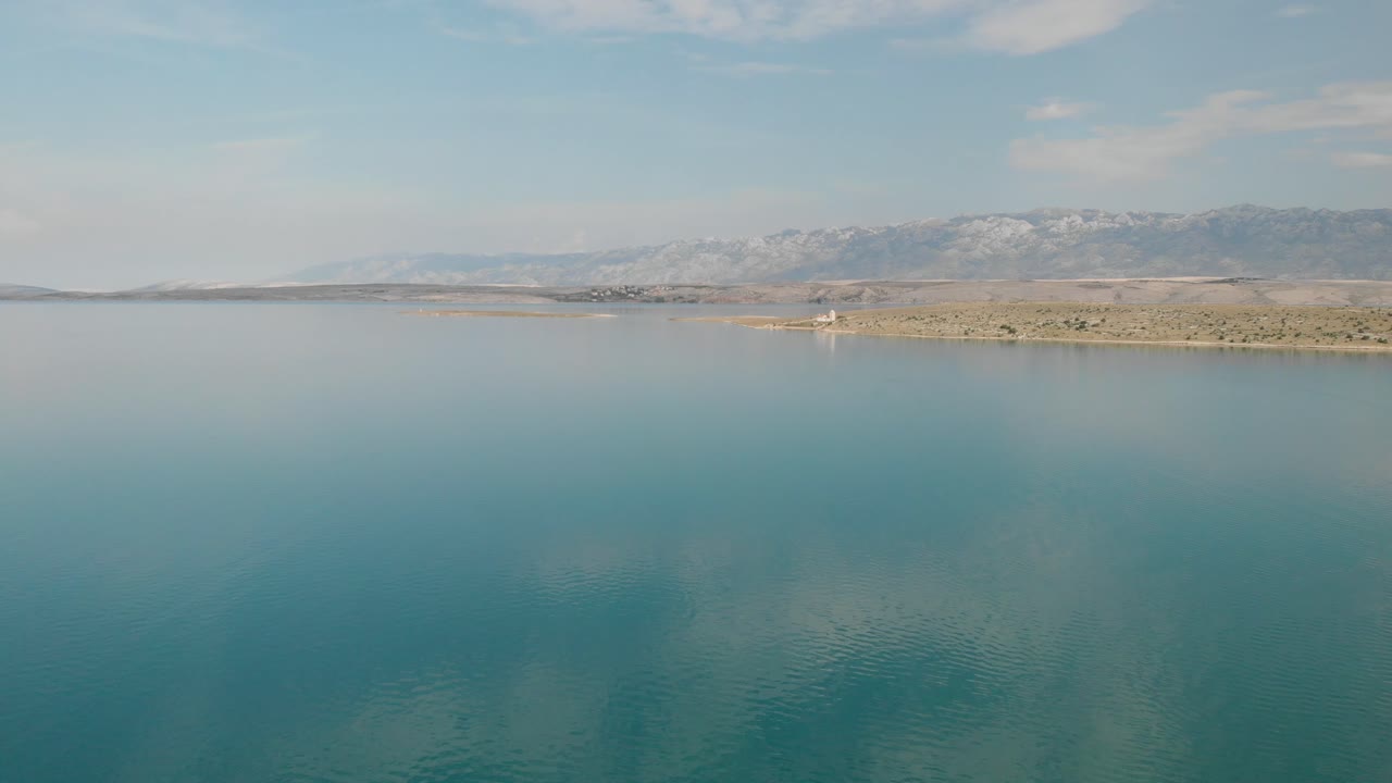 la tranquila superficie del mar adriático refleja nubes pálidas en una mañana temprana a fines del verano