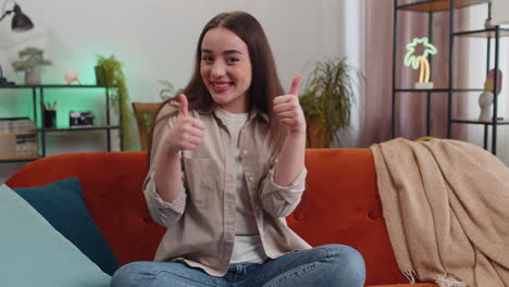 happy young woman looking approvingly at camera showing thumbs up, like positive sign, good news