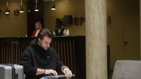 hombre usando una computadora portátil en el pasillo del hotel