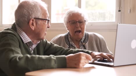happy elderly man and woman using laptop and credit card at nursing home