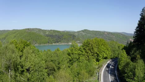 aerial - maneciu dam, forest and mountain road in romania, lowering wide shot