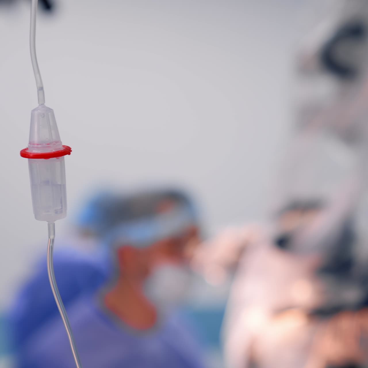 Contagocce con farmaci che gocciolano all'interno. Flebo in sala operatoria durante l'intervento. Sfondo sfocato