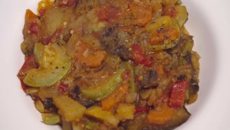 traditional spanish pisto on white plate, overhead rotating closeup