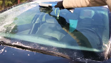 frozen window. removing ice from car`s front glass with scraper