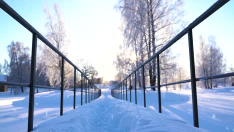 Sol-Brillante-En-El-Cielo-Sobre-Un-Paisaje-Invernal-Blanco-Con-Un-Pequeño-Puente,-Plataforma-Rodante-Hacia-Adelante