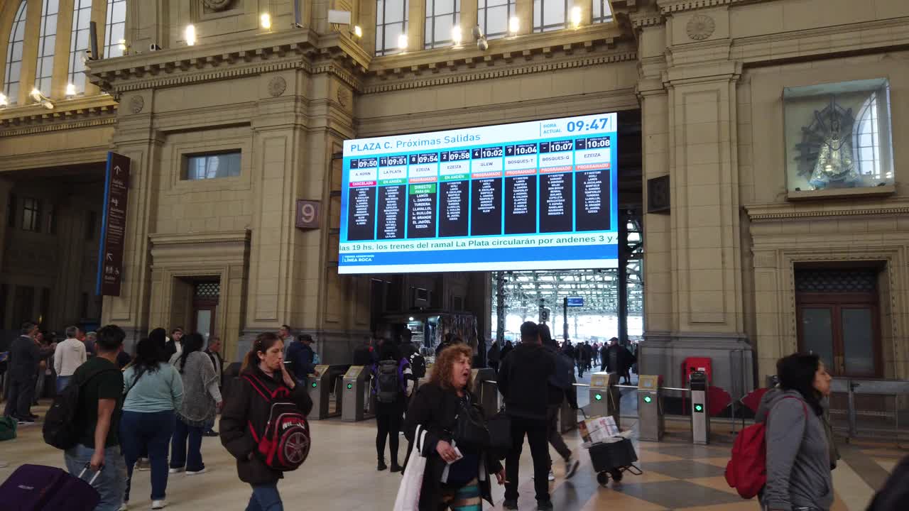 People commute inside central hall of Constitución railway station crowded Buenos aires area with train screen time information