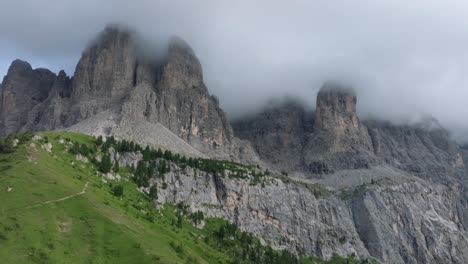 Toma-Aérea-De-Drones-Volando-Hacia-Adelante-De-Los-Picos-Escarpados-En-Passo-Gardena-Cubiertos-De-Nubes