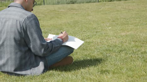 Toma-De-Mano-De-Un-Estudiante-Escribiendo-Notas-En-El-Parque