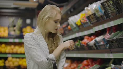 young beautiful brunette girl in her 20's picking out napa cabbage and cauliflower and putting them into shopping cart at the fruit and vegetable aisle in a grocery store