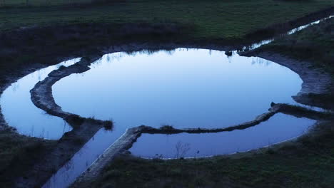 vista cinematográfica de un pájaro volando sobre una captación de agua circular durante las últimas horas de luz como un hechizo que se lanza sobre el cuerpo de agua