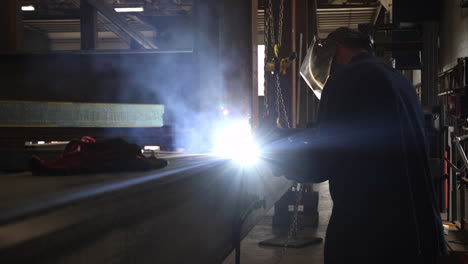 an industrial worker welding steel beams together in slow motion