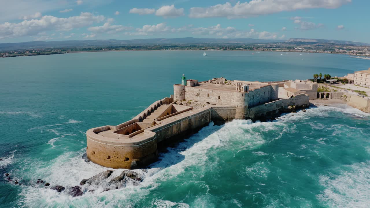 Aerial view of Medieval castle surrounded by Mediterranean sea in Ortigia, Sicily. Big waves crashing into the fortress walls. Castello Maniace in Ortigia island, Syracuse.