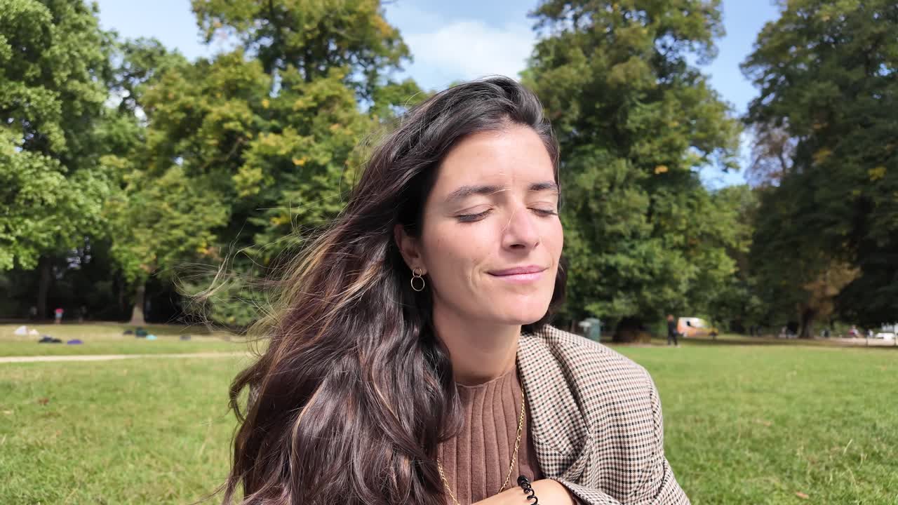 Young woman enjoying fresh air while sitting relaxed in a green city park