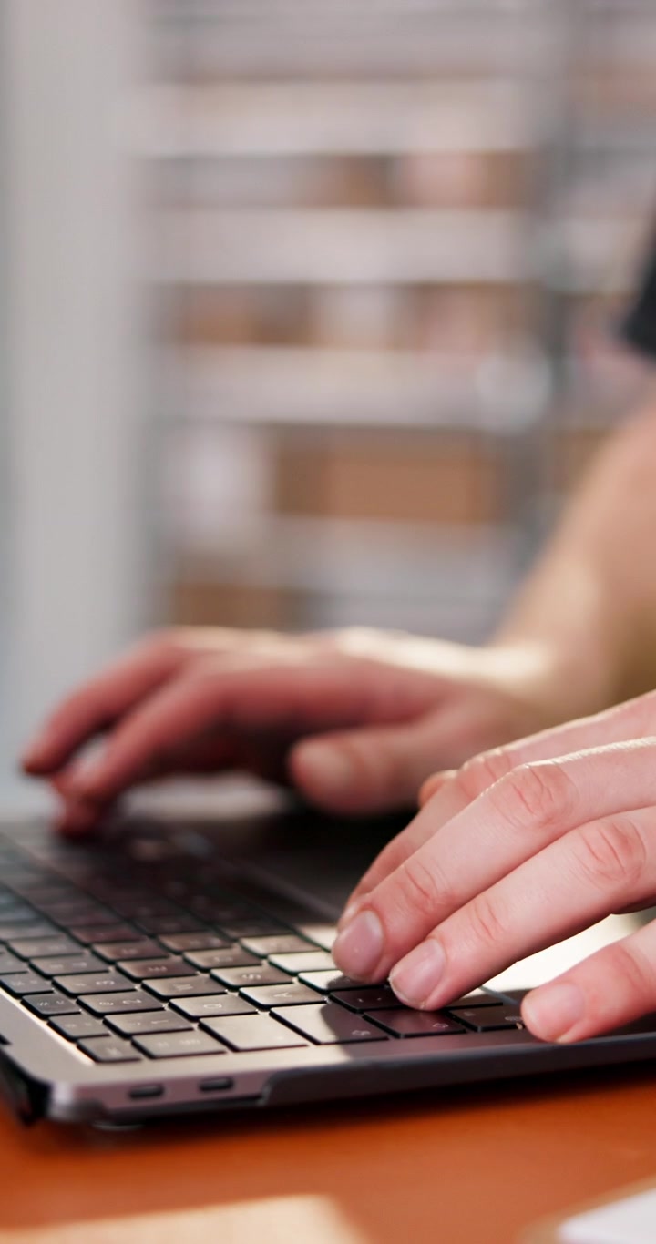 Primo piano di una persona che digita sulla tastiera del laptop in ufficio