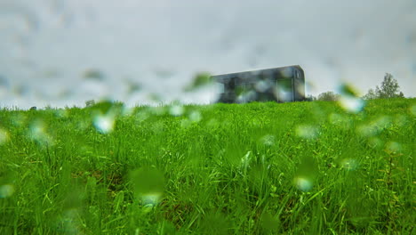 timelapse of an outbuilding on a grassy field as the clouds move in, creating darkness and rain begins to fall