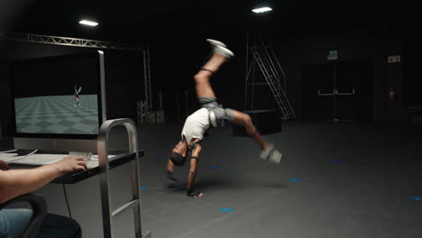 man wearing motion capture suit in studio performing backflip gymnastics actor wearing mo-cap suit for 3d character animation for virtual reality technology