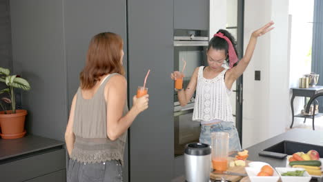 two young female friends enjoying drinks in a bright, airy modern kitchen at home