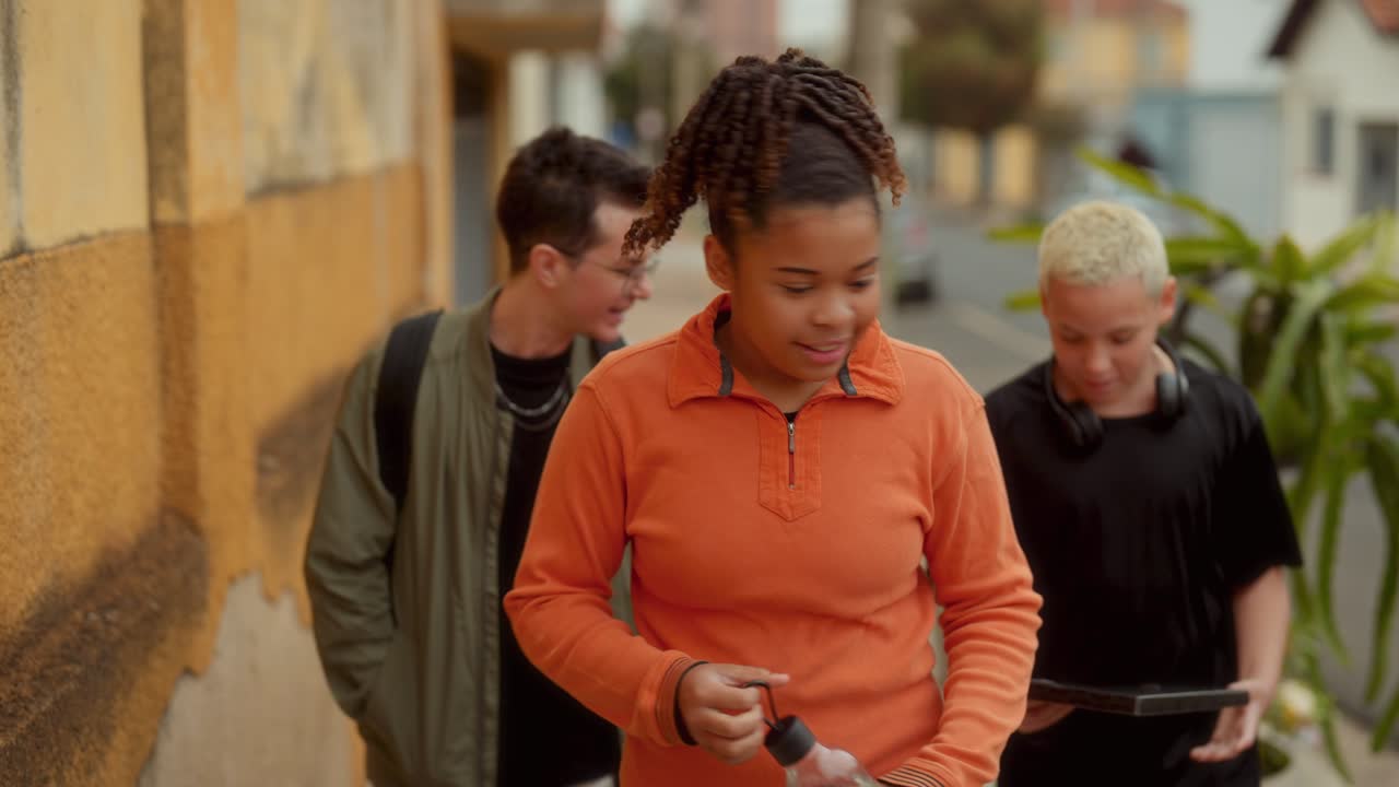 Three Young Friends Walking and Drinking Water on a City Sidewalk
