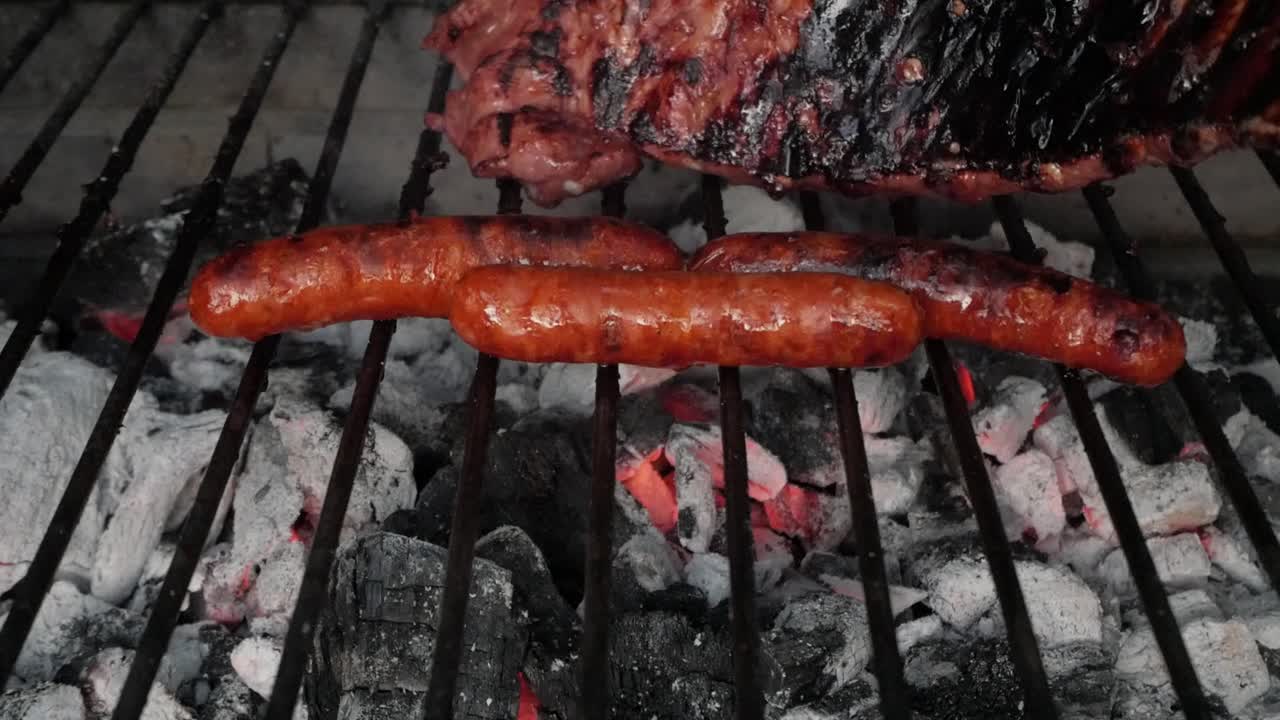 Juicy bbq sausages and grilled meat cooking over hot charcoal grill outdoors