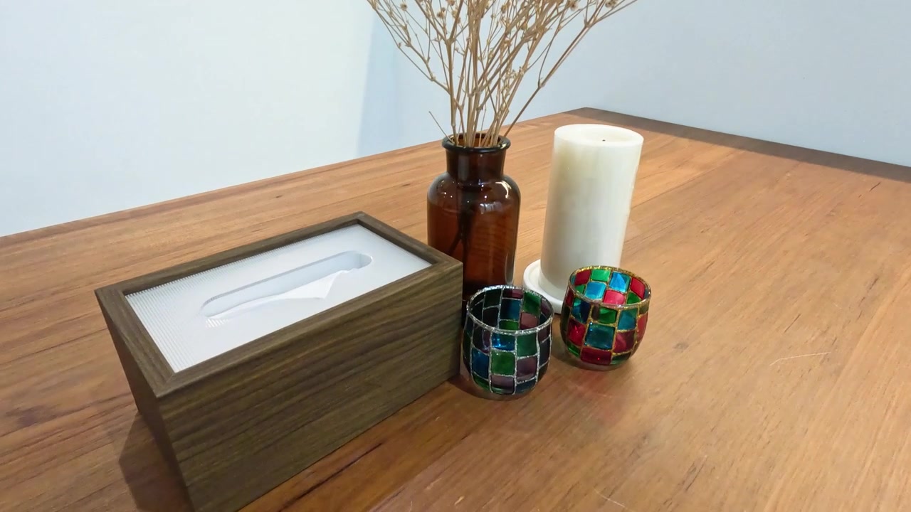 A top-down view of a wooden table featuring dried flowers, candles, and a tissue box