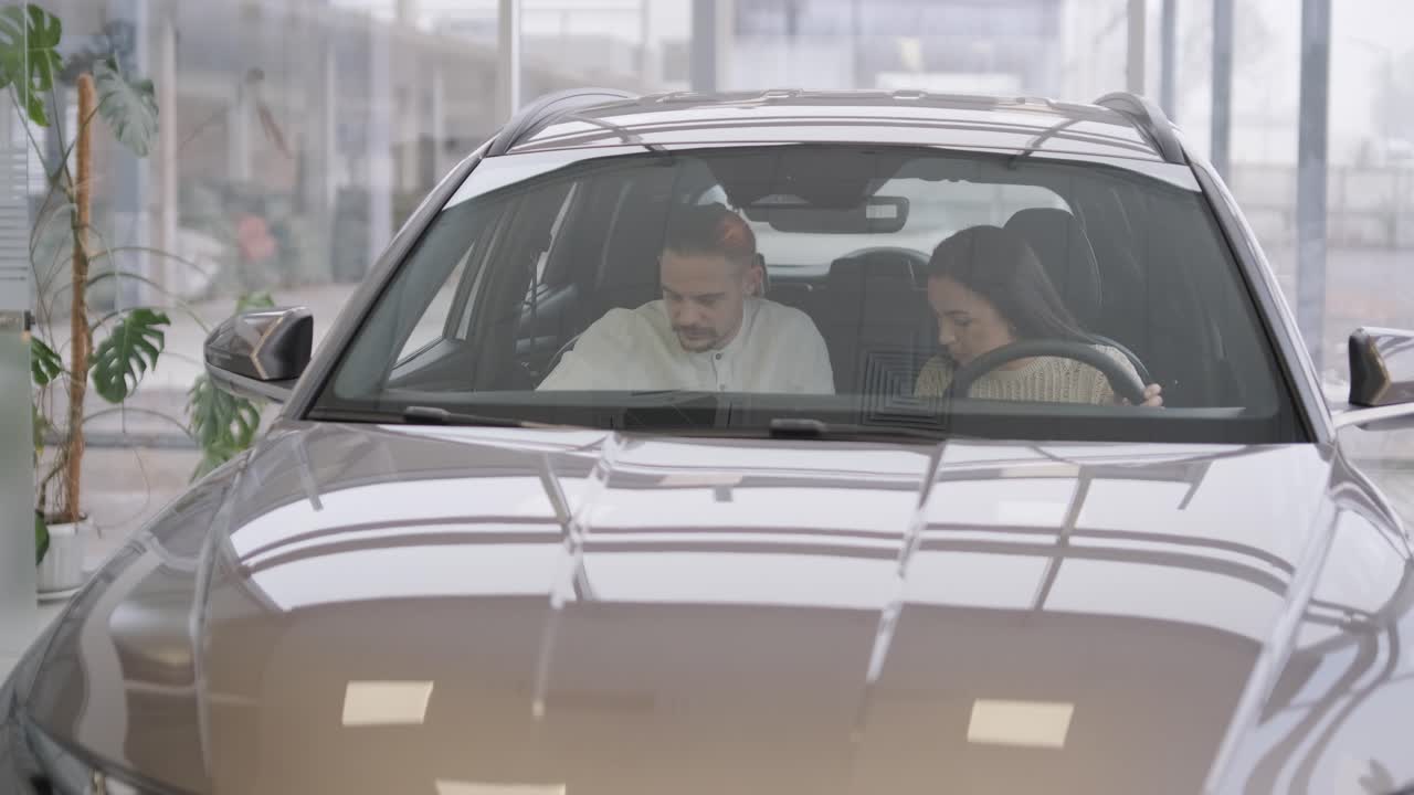 Bella giovane coppia all'autosalone scegliendo una nuova auto da acquistare.