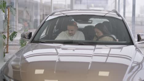 una hermosa pareja de jóvenes en la sala de exposición de automóviles eligiendo un coche nuevo para comprar.