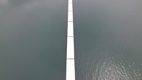 dolly aéreo de arriba hacia abajo del muelle y cubierta en mar tranquilo cerca de la costa de la playa de nacascolo, península de papagayo, costa rica