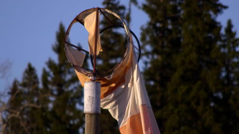 broken windsock with trees at background in fort saint james in canada