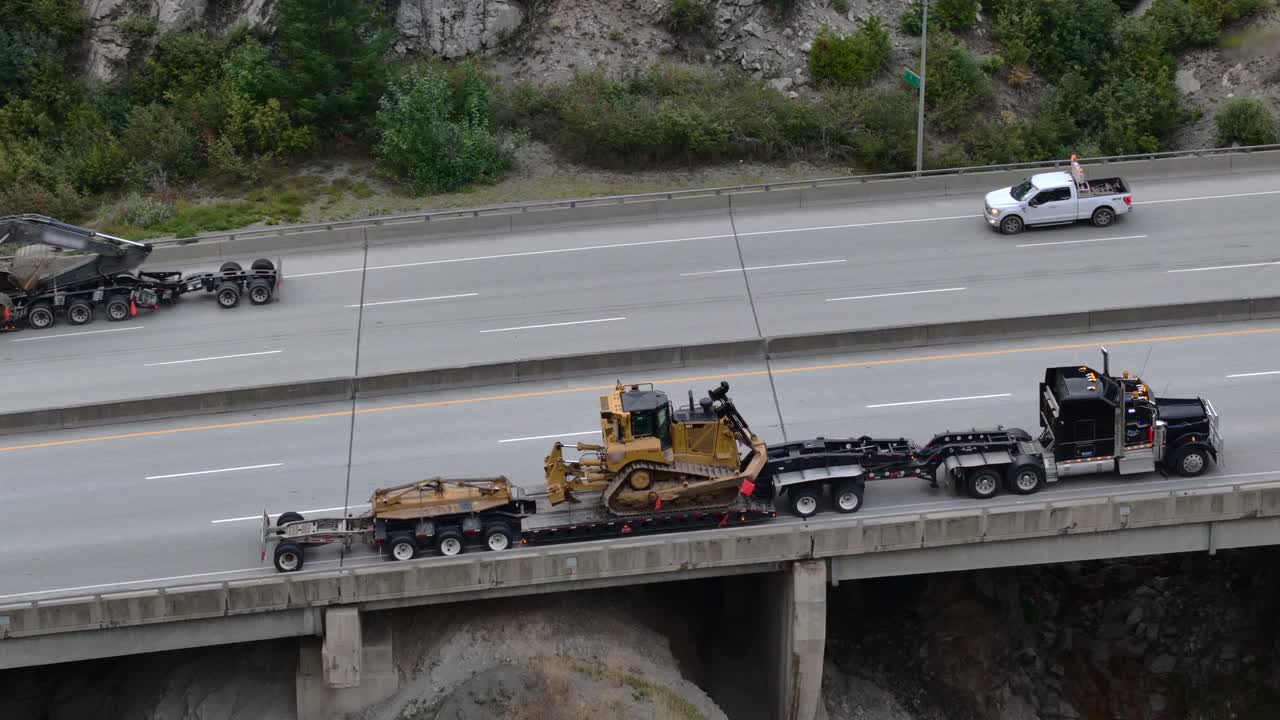 тяжелые перевозки на шоссе кокихалла, экскаватор и бульдозер перемещаются по крутому склону