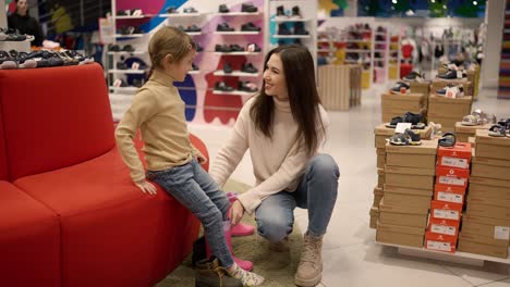 Mother-helping-daughter-to-try-on-shoes