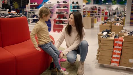 mother helping daughter to try on shoes